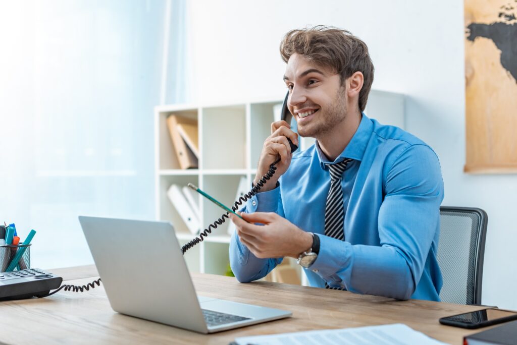 smiling travel agent talking on phone while holding pencil